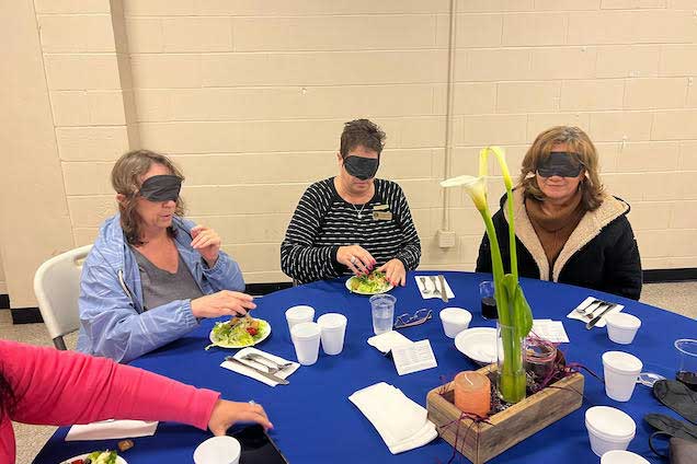 Blindfolded diners at blue table.